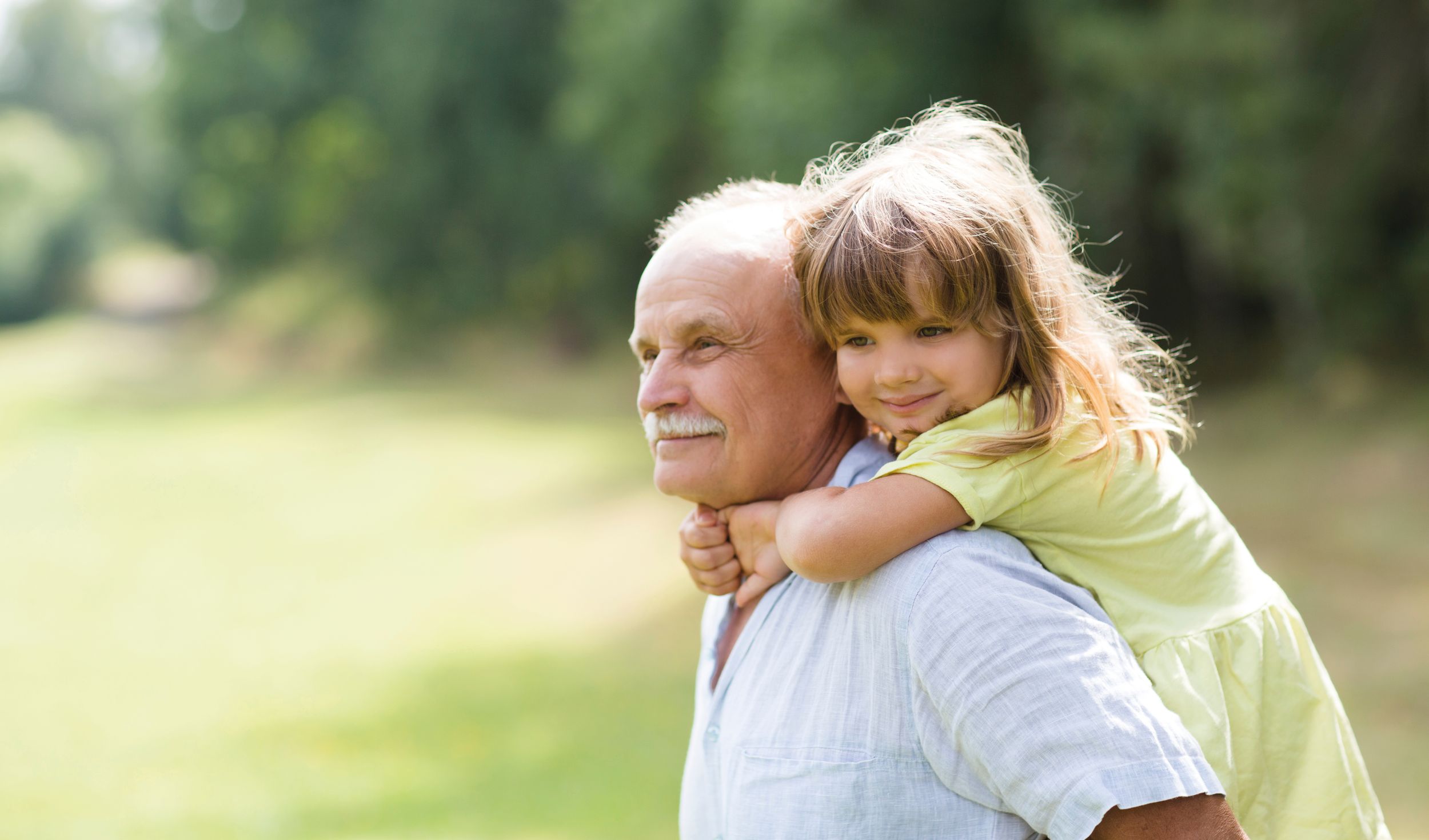 Little child girl hugs grandpa On Walk in the summer outdoors. Concept of friendly family.